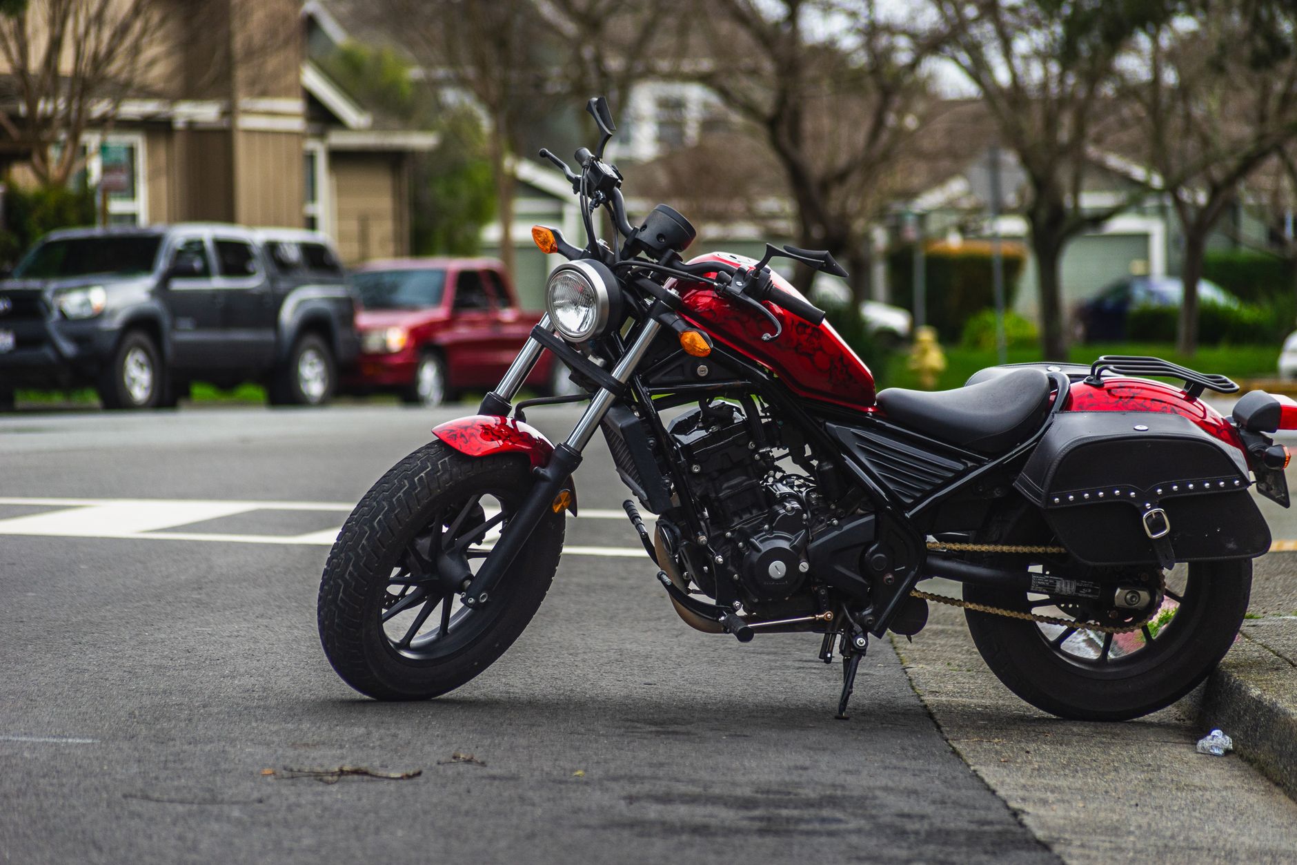 Moto vermelha estacionada em uma rua arborizada